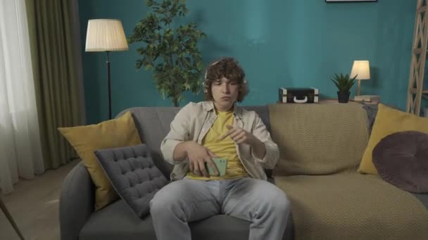 Oturma Odasındaki Kanepede Günlük Giysiler Içinde Oturan Genç Bir Erkek — Stok video