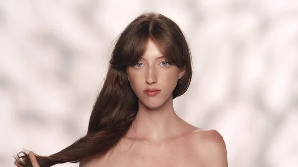 魅力的な若いブルネットの肖像画 青い目をした少女モデルが輝く髪を抱え カメラを見つめている ビューティー広告コンセプト — ストック写真