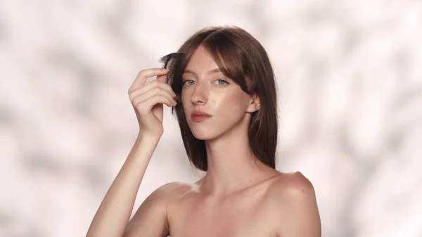 美しいブルネットガールモデルの肖像画 白人女性が黒い羽で肌に触れ カメラにポーズをとった スキンケア広告コンセプト — ストック写真