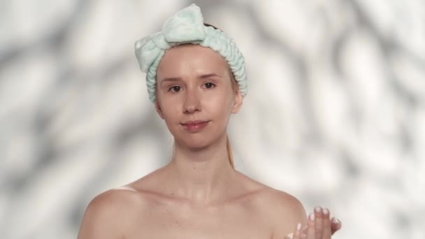 女人在脸上涂上绿色的化妆品面具 显赫的妇女与头发乐队在工作室灰色背景与亮点 护肤和治疗 — 图库视频影像