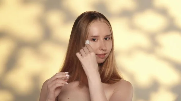 여성은 주름을 방지하기 주위의 피부에 사용합니다 하이라이트와 노란색 배경에 스튜디오에서 — 스톡 사진