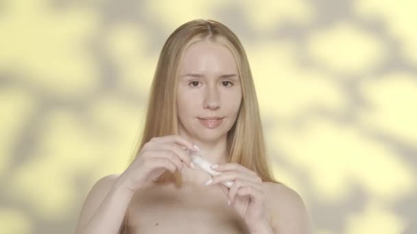 여성은 주름을 방지하기 주위의 피부에 사용합니다 하이라이트와 노란색 배경에 스튜디오에서 — 비디오