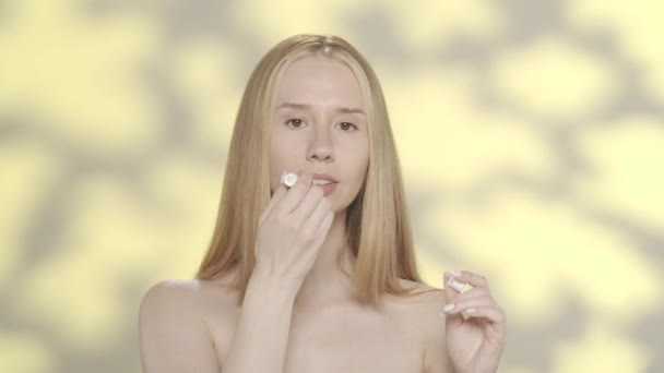 年轻妇女使用卫生的唇膏 在带有亮点的黄色背景下 在演播室里表现突出的女人 化妆品和化妆品 唇部护肤概念Hdr Bt2020 Hlg材料 — 图库视频影像
