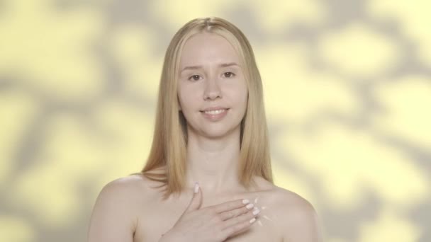 Egy Krémet Tesz Mellei Nyílt Bőrére Félmeztelen Stúdióban Sárga Háttérrel — Stock videók