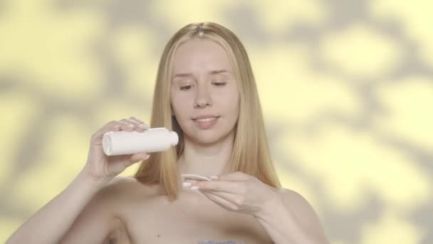 여성은 패드를 사용하여 미세한 얼굴에 바릅니다 하이라이트와 노란색 배경에 스튜디오에서 — 비디오