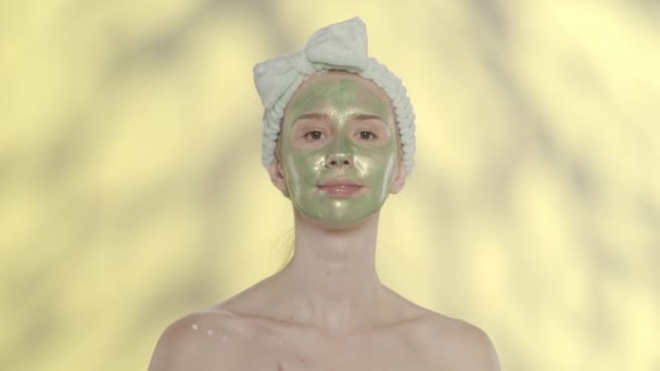 Una Mujer Con Una Máscara Cosmética Verde Cara Frota Crema — Vídeo de stock