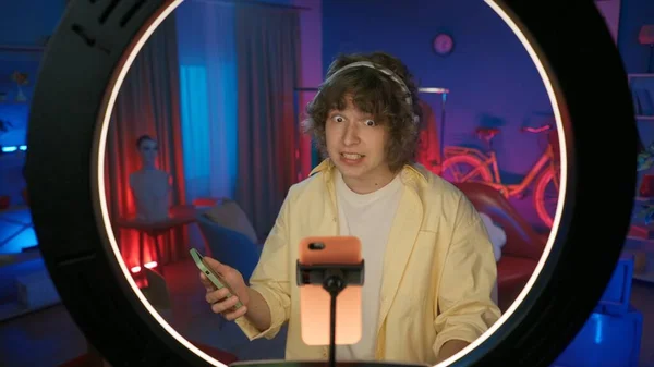 戴耳机的年轻男性维基百科 谈论新音乐 拿着智能手机 在镜头前 拍到一个男人在家里的镜头 — 图库照片