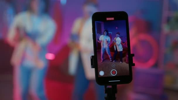 专注于智能手机的展示 一对年轻夫妇在家庭工作室为社交网络拍摄了一段视频 男男女女在电话摄像机前跳舞 响彻着灯光 社交媒体概念 — 图库视频影像