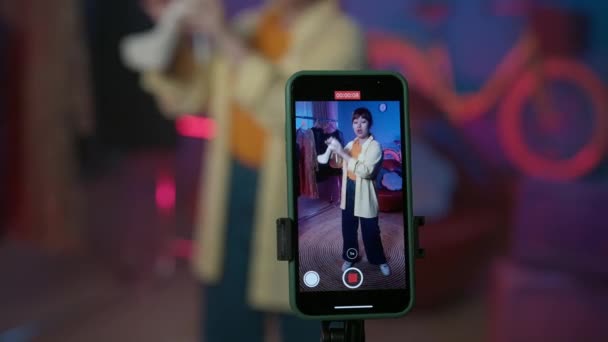 スマートフォンディスプレイに焦点を当て ガールブロガーは新しいホワイトハイヒールシューズを宣伝します ホームスタジオで携帯電話カメラのリングライトの前にビデオを撮影する女性Voogger — ストック動画