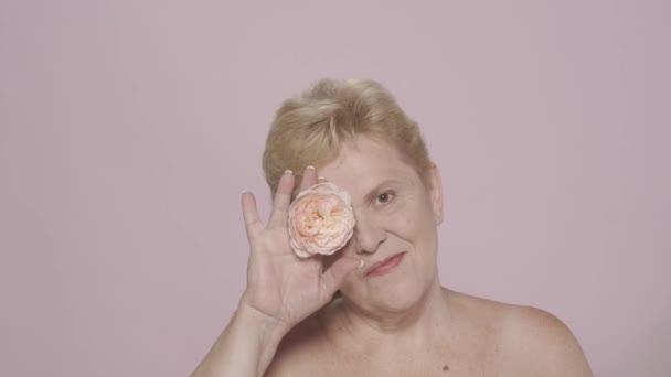 一个优雅的老年妇女的画像 一个中年模特儿紧紧抓住她的近照 用玫瑰花遮住她的眼睛 看着相机 美容美发广告概念Hdr Bt2020 Hlg — 图库视频影像