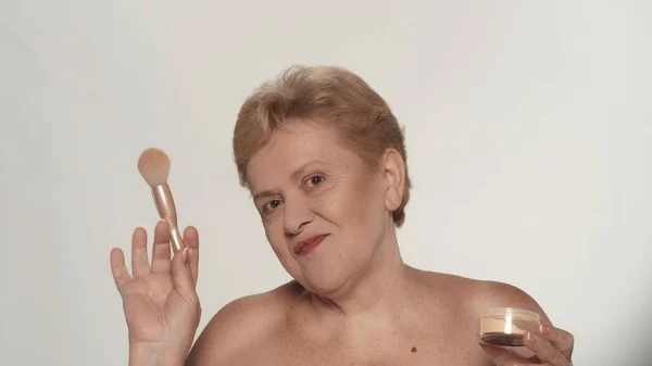 美しい上級女性の肖像画 ブラシを使って顔にミネラル化粧品の粉を塗った中年の女性モデルのクローズアップショット 美容メイク広告コンセプト — ストック写真