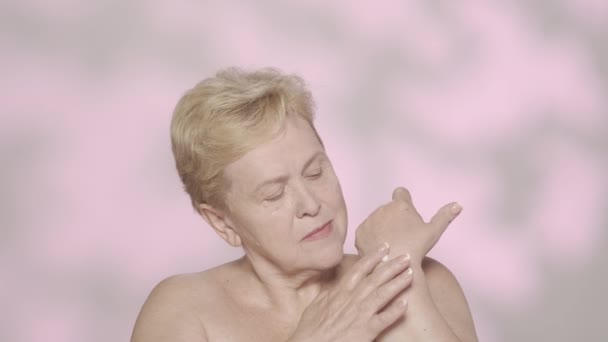 一个漂亮的金发老妇人的画像 一个中年女性模特的近照 她用了护手霜 看着相机 护手品广告概念 慢动作人类发展报告 — 图库视频影像