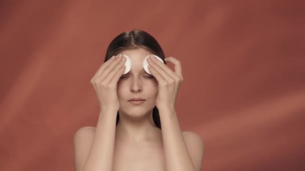 Egy Vigyáz Bőrére Stúdióban Vörös Háttérrel Közelről Egy Szemináriumi Vattapamacsokkal — Stock videók