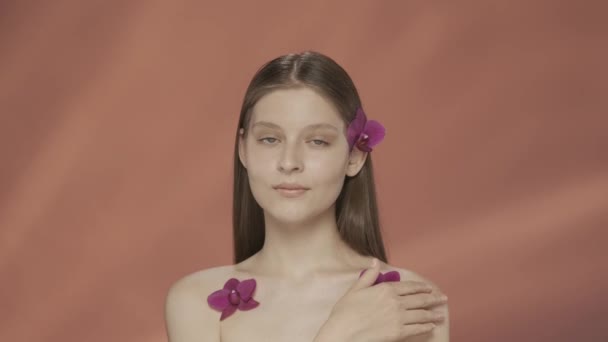 Молодая Женщина Орхидеями Волосах Плечах Касается Своей Обнаженной Кожи Портрет — стоковое видео