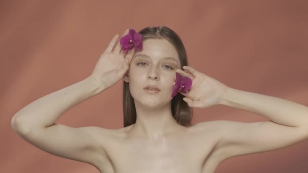Женщина Прикасается Своей Идеальной Коже Цветами Орхидей Наслаждаясь Косметическим Эффектом — стоковое видео