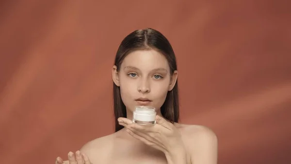 一个女人拿着一罐化妆品霜 显赫的女人与一罐奶油在工作室的红色背景 关怀的概念 — 图库照片