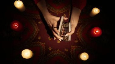 Falcı seansı sahnesi. Tarot kartları karıştıran, masanın üzerinde duran bir sürü mum olan kadın manken ellerini yakın mesafeden çek. Kehanet hazırlığı. Esrarengiz kavram.