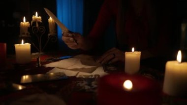 Bir sürü mum ve tarot kartlarıyla dolu bir masa resmi. Kadın güzel bir tüy kalem alır ve parşömen kağıdına bir şeyler yazar. Sihirli estetik konsept.