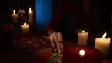 Odadaki masanın etrafındaki mumlarla yakın plan çekimini yap. Güverteden tarot kartları çıkaran bir kadın, bir plan yapıyor. Öngörü kavramı.