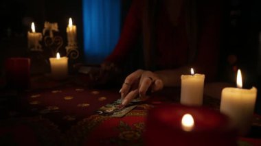 Odadaki masanın etrafındaki mumlarla yakın plan çekimini yap. Kadın model, masadaki güverteden bir sürü tarot kartı çıkarıyor. Kişisel kehanet kavramı.