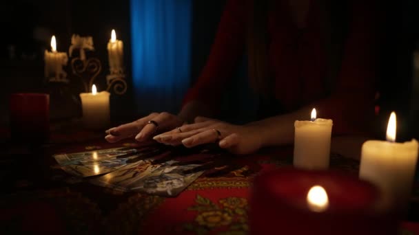 房间里桌子的近景镜头 周围有许多蜡烛 女人把手放在塔罗牌的扇子上 把它们从桌上拿开 占卜概念 — 图库视频影像