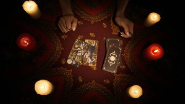 Falcı seansı sahnesi. Güverteden bir kaç tarot kartı alıp masaya koyan bir kadın eli yakın çekim. Esrarengiz kehanet.