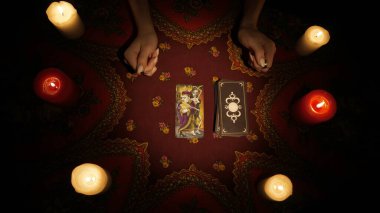 Falcı seansı sahnesi. Güverteden bir tarot kartı alıp masanın üzerine koyan bir kadın eli yakın çekim. Esrarengiz kehanet.