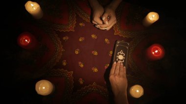Falcı seansı sahnesi, üst manzara. Bir kadının el ele tutuşup kadın müşteriye bir deste tarot kartı sunduğu yakın plan çekimler. Müşteri birkaç kart seçer. Esrarengiz kavram.