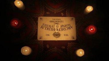 Sihirli seans sahnesi. Masanın üzerinde alfabe olan ruhani tahtayı yakın çekim, etrafında bir sürü mum var. Esrarengiz kehanet kavramı.