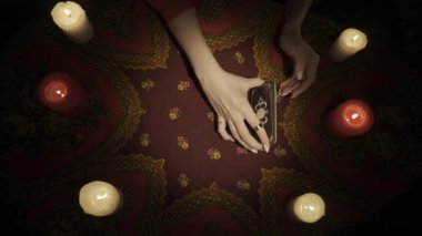 Falcı seansı sahnesi, üst manzara. Bir kadının birkaç tarot kartının fanı masaya yerleştirirken ve bir kartın anlamını kameraya gösterirken yakın çekim görüntüsü. Kehanet kavramı. HDR