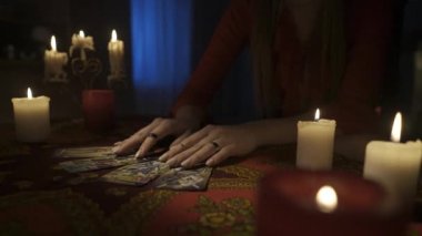 Odadaki masanın etrafındaki mumlarla yakın plan çekimini yap. Kadın kendi yaptığı masadaki tarot kartlarının düzenini kaldırıyor. Kehanet kavramı. HDR BT2020 HLG Malzemesi.