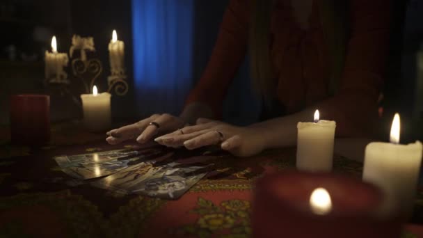 房间里桌子的近景镜头 周围有许多蜡烛 女人把手放在塔罗牌的扇子上 把它们从桌上拿开 占卜的概念 Hdr Bt2020 Hlg Material — 图库视频影像
