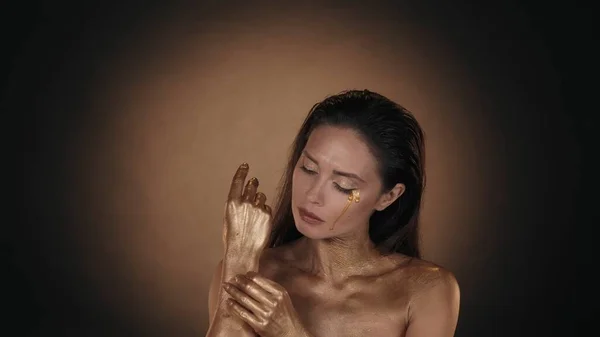 魅力的な女性の肖像画 彼女の肌から乾いた塗料を取り除く黄金の塗料の涙で女性モデルのクローズアップショット クリエイティブ広告コンセプト — ストック写真