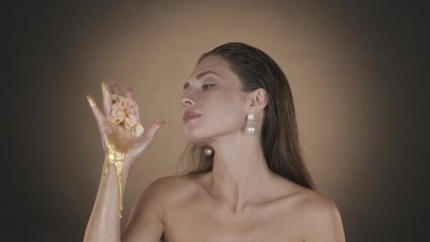 美しいブルネットの女性の肖像画 彼女の手から流れる黄金の絵を見て それに触れる真珠のイヤリングを持つ女性モデルのクローズアップショット 美容広告コンセプト Hdrについて — ストック動画