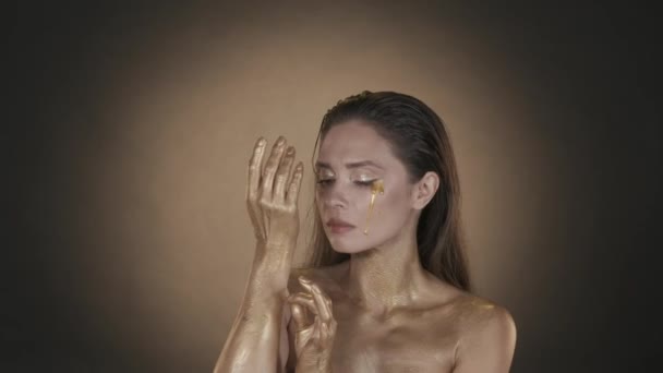一个漂亮女人的画像 一个女性模特的近照 妆容光彩夺目 胸部和肩膀上闪烁着颤动 从她手上的皮肤上剥去了干金色的油漆 美容广告 — 图库视频影像