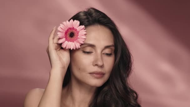 Μια Γυναίκα Έχει Ένα Λουλούδι Ζέρμπερα Στο Τέλειο Δέρμα Της — Αρχείο Βίντεο