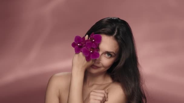 Kobieta Usuwa Rękę Kwiatami Orchidei Twarzy Pokazując Czystą Gładką Skórę — Wideo stockowe