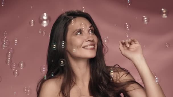 Χαρούμενη Παιχνιδιάρα Γυναίκα Περιτριγυρισμένη Από Σαπουνόφουσκες Στο Στούντιο Ροζ Φόντο — Αρχείο Βίντεο