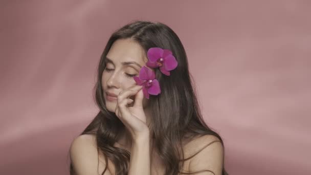 Женщина Распускает Бархатный Фиолетовый Цветок Орхидеи Своей Чистой Коже Портрет — стоковое видео