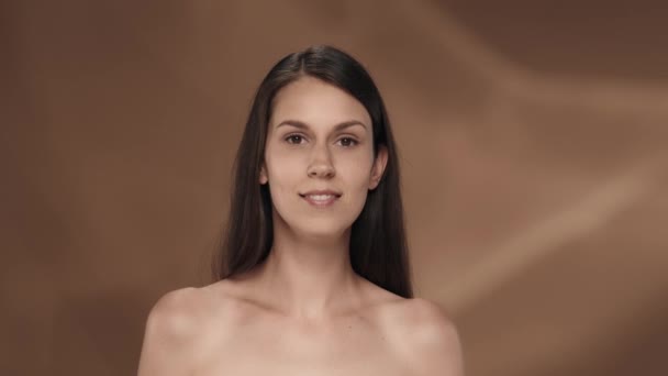 여자는 피부를 돌보고 얼굴에 크림을 바릅니다 배경에 스튜디오에서 세미나 여자의 — 비디오