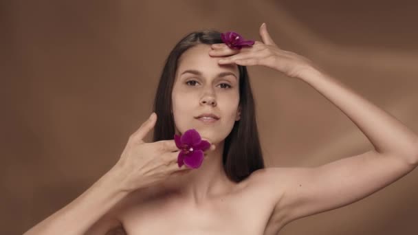 Женщина Орхидеями Руках Касается Лица Наслаждаясь Гладкой Мягкой Кожей Портрет — стоковое видео