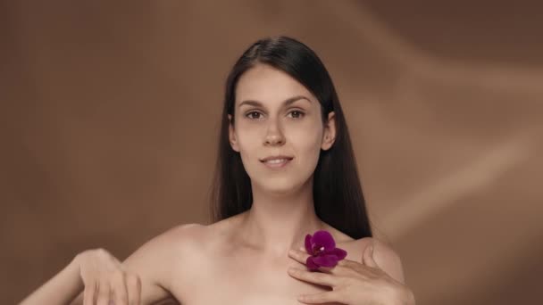 Bir Kadın Orkide Çiçeğiyle Gözlerini Kapatır Stüdyodaki Kahverengi Arka Planda — Stok video