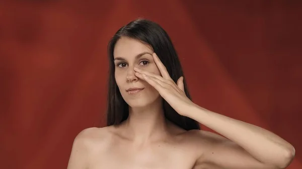 女性は彼女の目の下の皮膚に触れ しわの不在を示しています 赤い背景の女性の肖像画が閉じられています 自然の美しさ プラスチック手術 化粧品 ケアの概念 — ストック写真