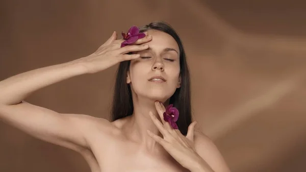 Eine Frau Mit Orchideenblüten Ihren Händen Berührt Ihr Gesicht Und — Stockfoto