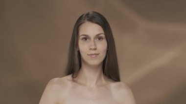 Bir seminer kadını, kahverengi bir arka planda, ellerinin yumuşaklığının ve kadifeliğinin tadını çıkarır. Güzellik, kozmetoloji, el bakımı HDR BT2020 HLG Malzeme.