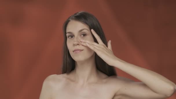 女性は彼女の目の下の皮膚に触れ しわの不在を示しています 赤い背景の女性の肖像画が閉じられています 自然の美しさ プラスチック手術 化粧品 ケアの概念 Hdrについて — ストック動画