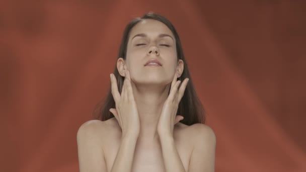 一个女人表现出她完美的皮肤和正常的面部特征 一个身披红色背景的精液女子的画像 自然美 整形手术 护理的概念 — 图库视频影像