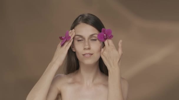 Kobieta Kwiatami Orchidei Rękach Dotyka Twarzy Ciesząc Się Gładką Miękką — Wideo stockowe