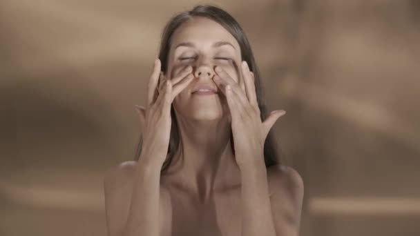 女性は顔 肩の皮膚に触れ 化粧効果を楽しんでいます ブラウンの背景にあるスタジオのセミノードの女性 美しさ 化粧品 ケアHdr Bt2020 Hlg材料 — ストック動画