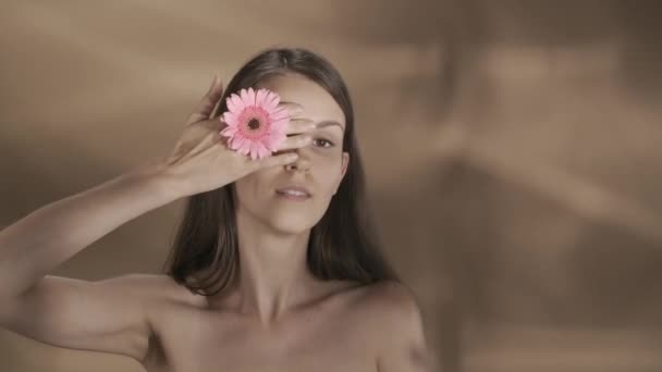 게르베라 꽃으로 그녀의 손으로 그녀의 그녀의 어깨의 피부에 하이라이트와 배경에 — 비디오